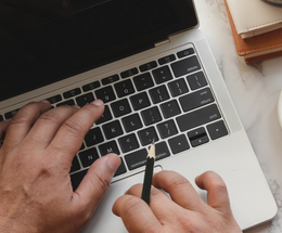 A person&#039;s hands typing on the keys of a laptop computer.