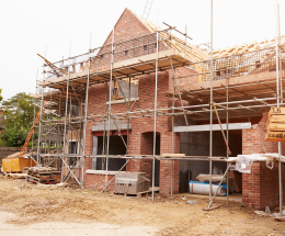 Partially completed detached house with scaffolding around the exterior.