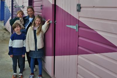Image of Mother and three children besides the renovated beach huts.