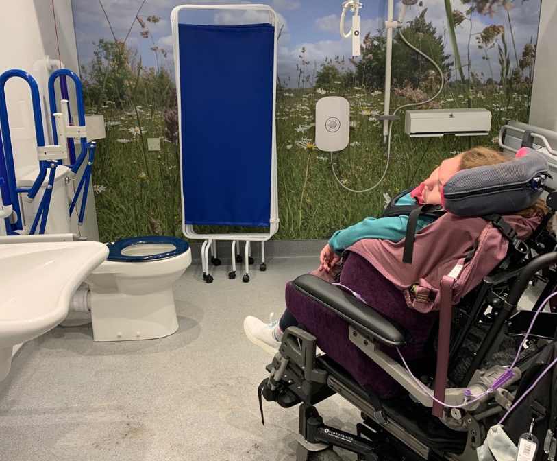 A girl in a wheelchair in a Changing Places toilet