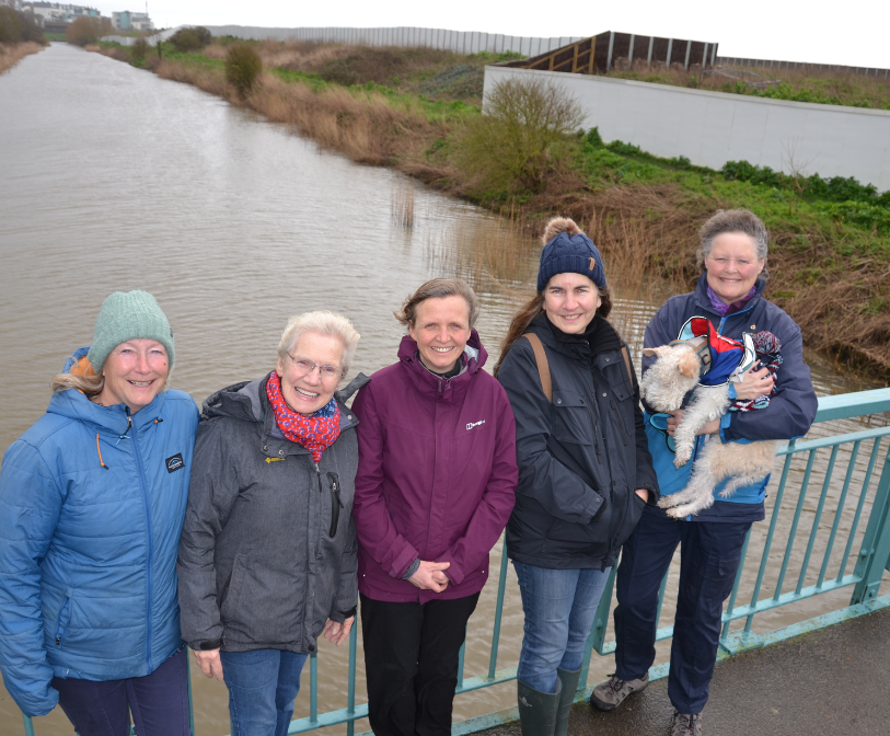 A photograph of five people (councillors and campaigners) in front of the Princes Parade hoarding set for removal.