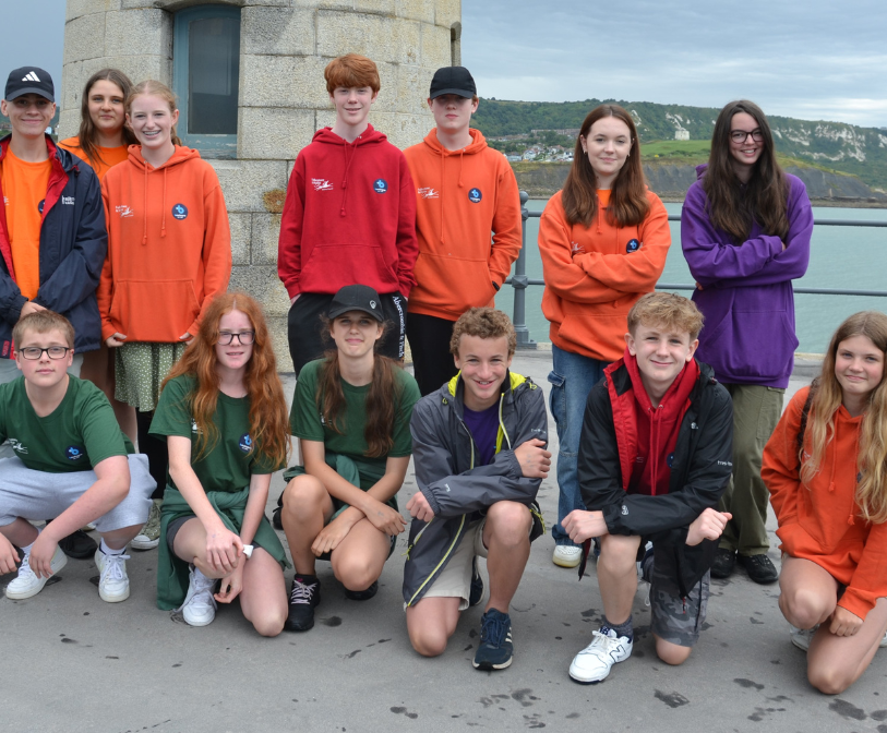 A group photo of members of the Tall Ships 2023 trip standing on the Folkestone Harbour Arm.
