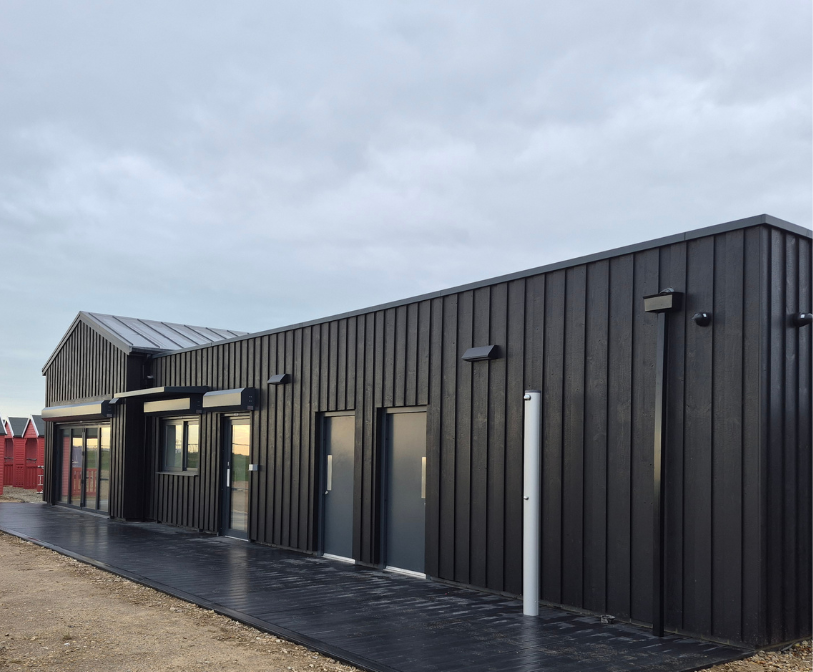 A photograph of the new Changing Tides Coastal Centre, with beach huts in the background.