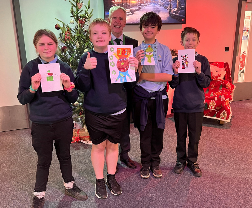 Four Beacon School learners pictured with their Christmas card designs and council leader, Cllr Jim Martin.