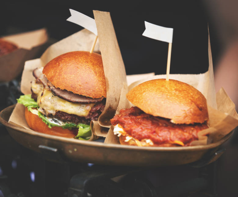 An image of two burgers being handed out at a local food market