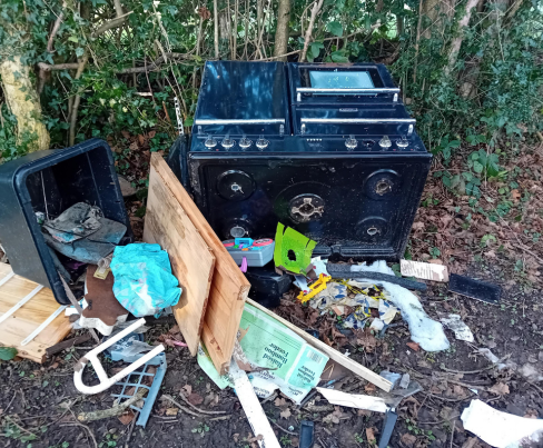 A cooker and household rubbish dumped beside a road in Acrise.