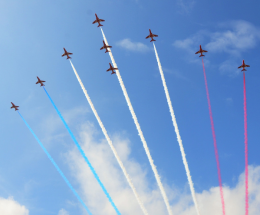 Red Arrows planes flying in sky with red, white and blue smoke plumes